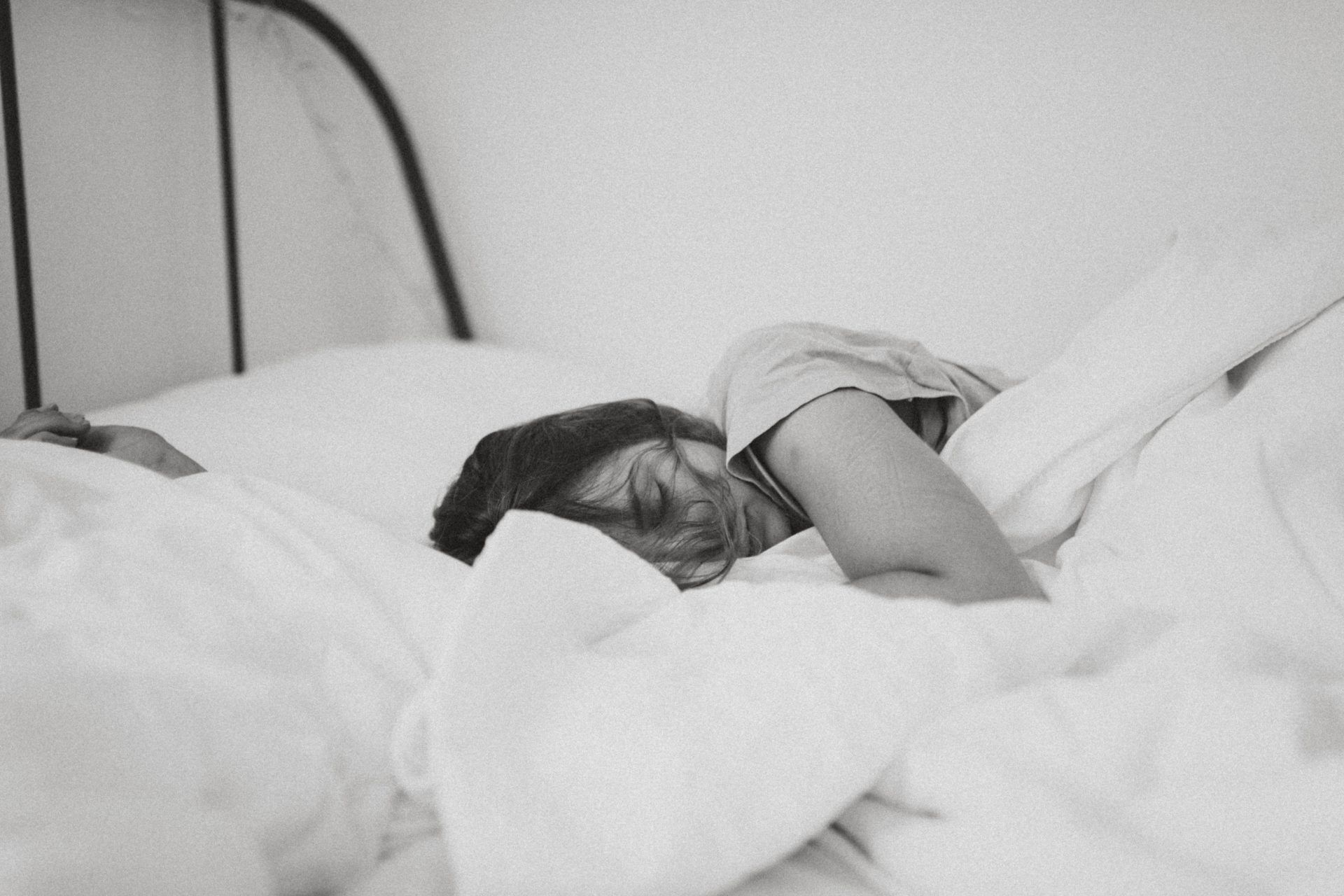 grayscale woman lying on bed